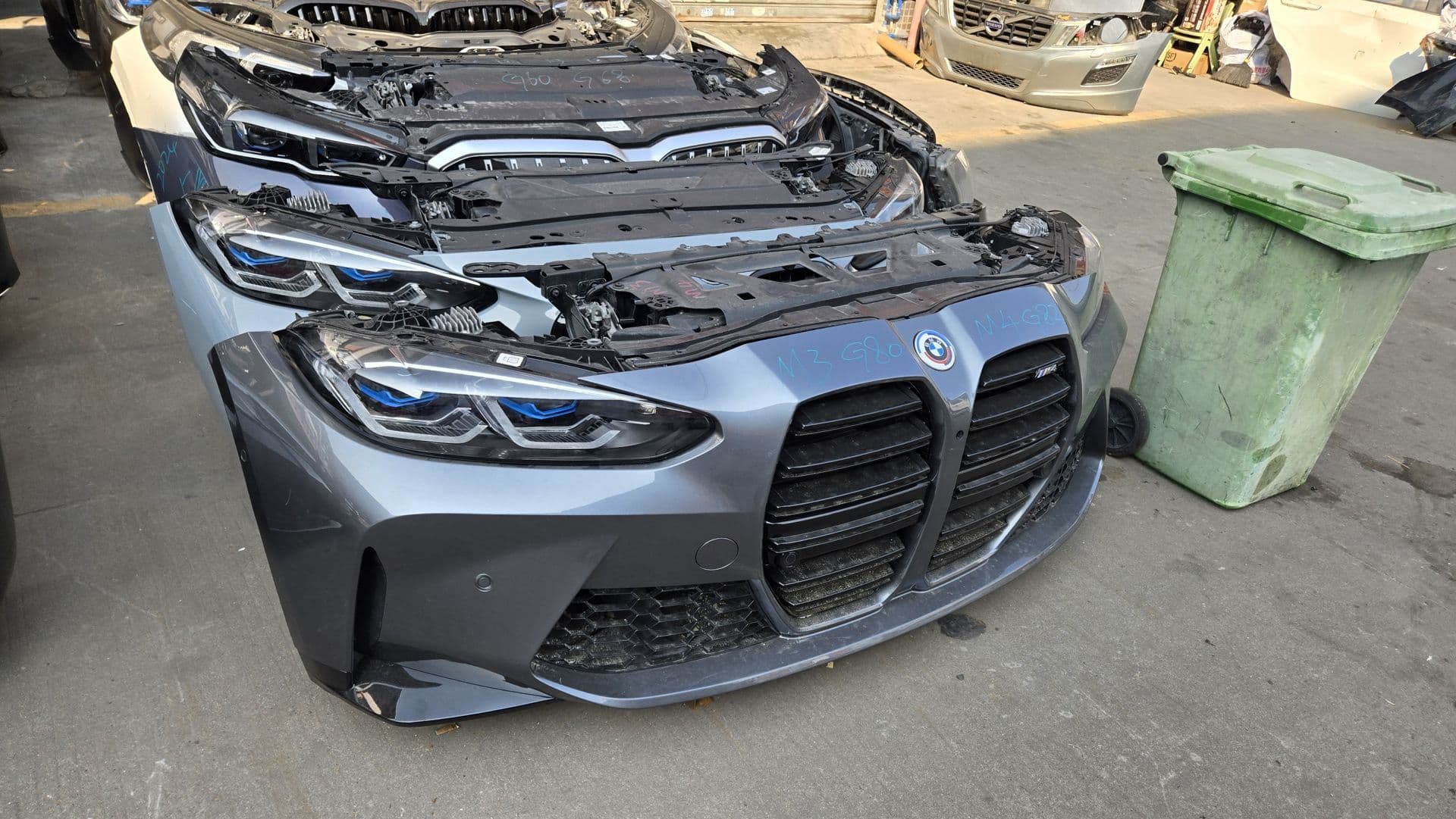 A row of BMW M3 and M4 front clips lined up on the shop floor